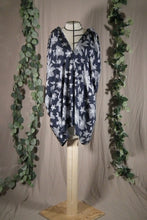 Load image into Gallery viewer, A long pleated skirt in a drapey rayon print that's dark blue with white flowers is displayed on a dress form as a swim coverup, showing the front view. The slit makes a deep V at the neck. In the background are some fake green vines.