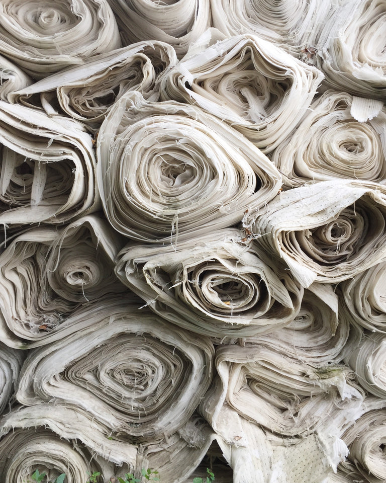A pile of rolls of white fabric, viewed from the ends. 